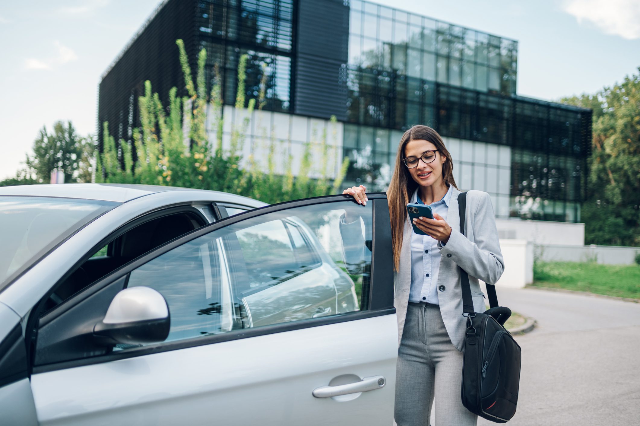 A woman standing next to her car and holding onto the door handle.
