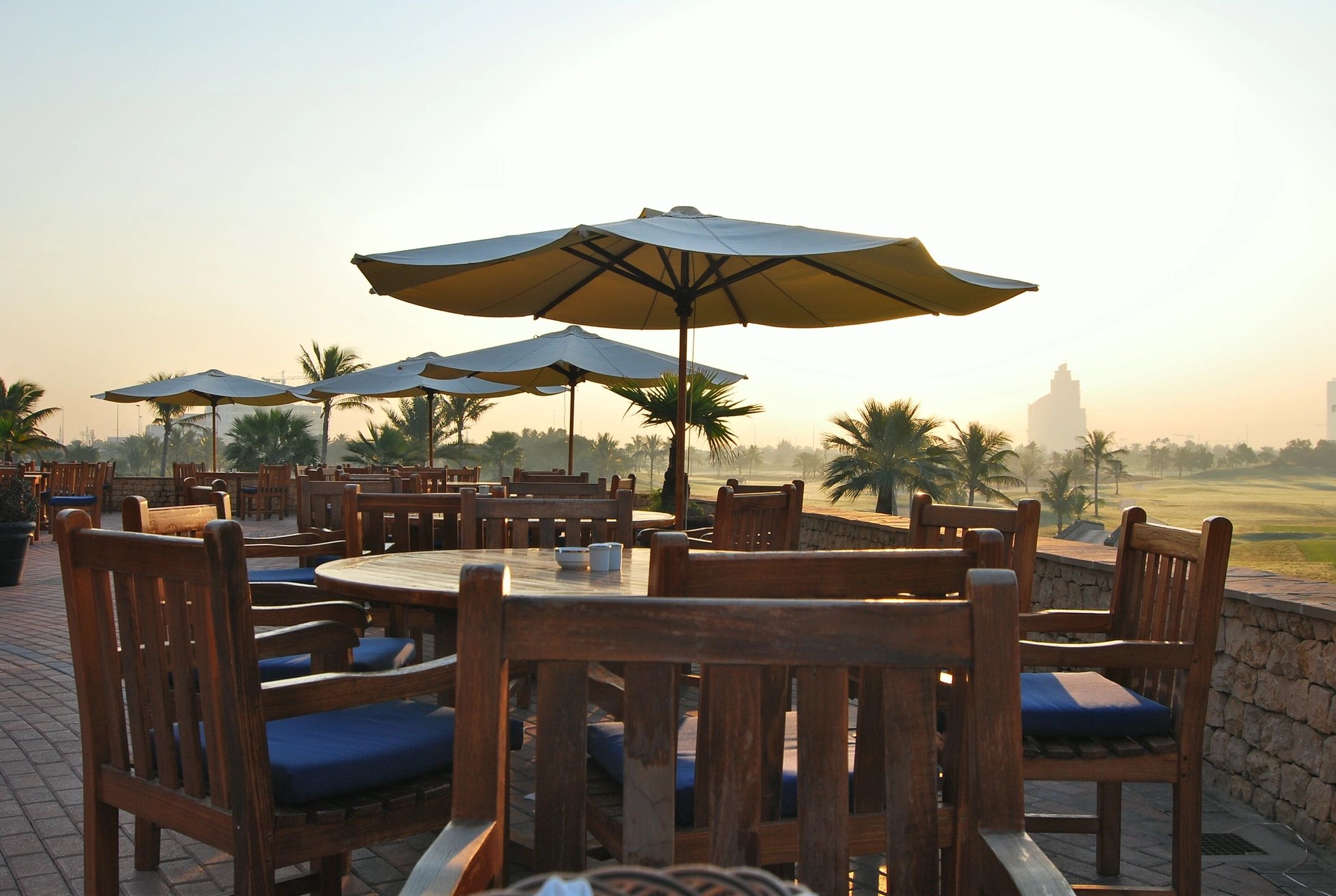A large wooden table with chairs and umbrellas