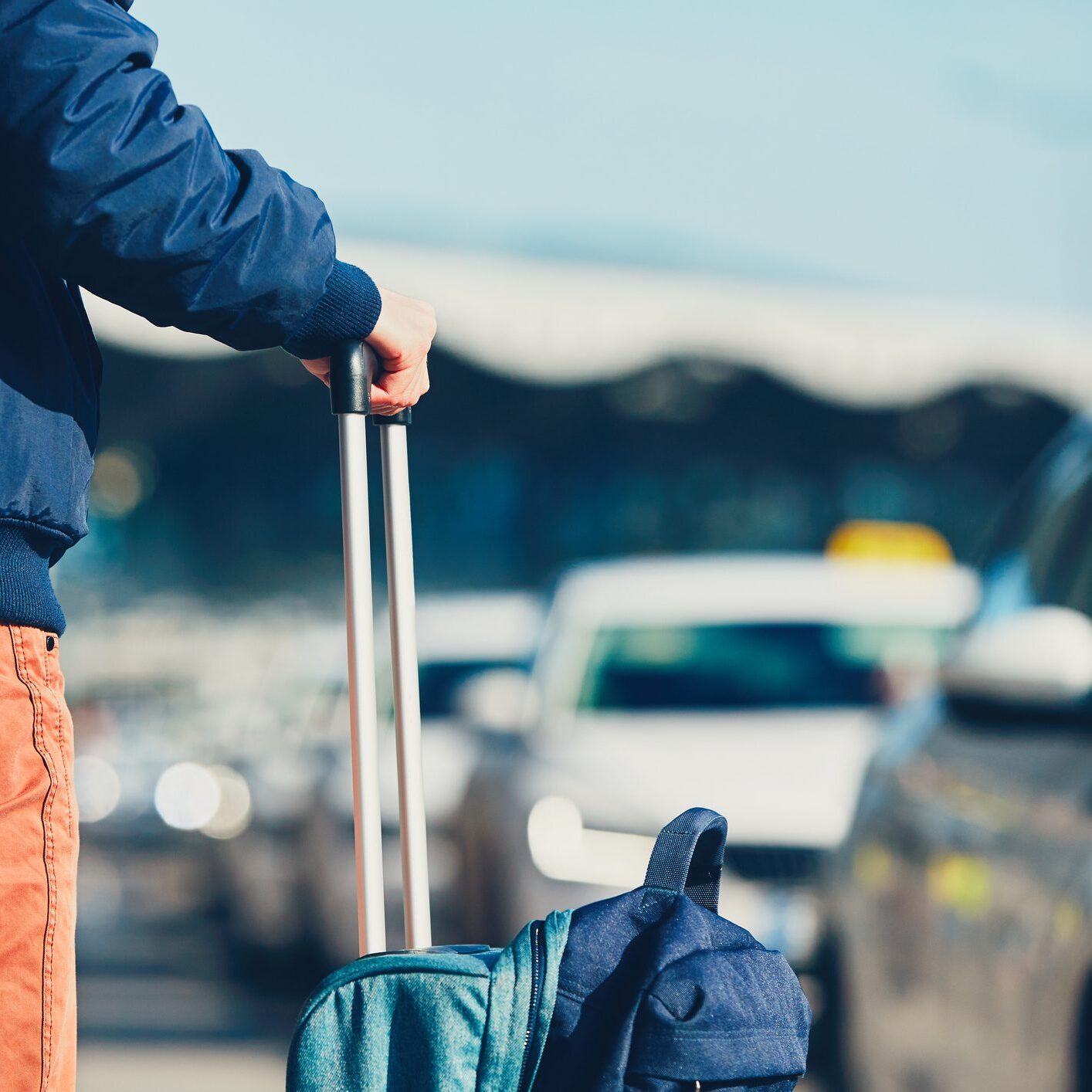 A person holding onto luggage on the side of road.