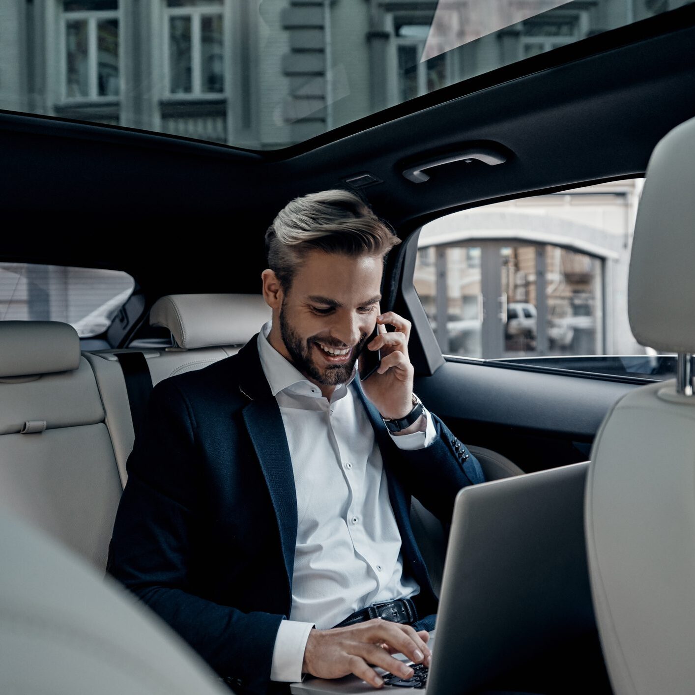 A man sitting in the back of a car on his phone.