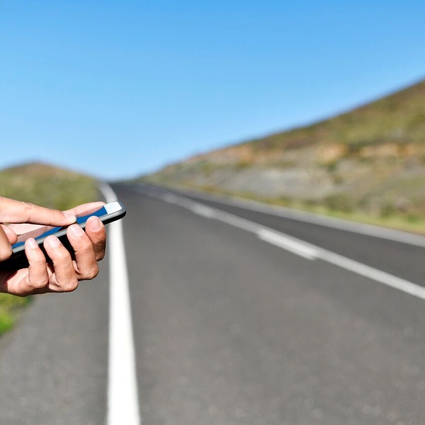 fm=f_npePm2P A person holding a cell phone on the side of a road.